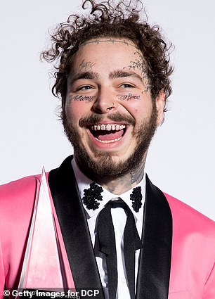 Post Malone in a pink suit, looking dapper and smiling.